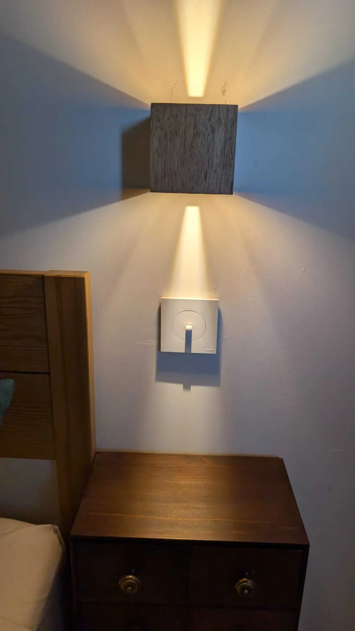 Applique murale cubique en bois allumée et interrupteur Schneider Odace blanc au-dessus d'une table de chevet