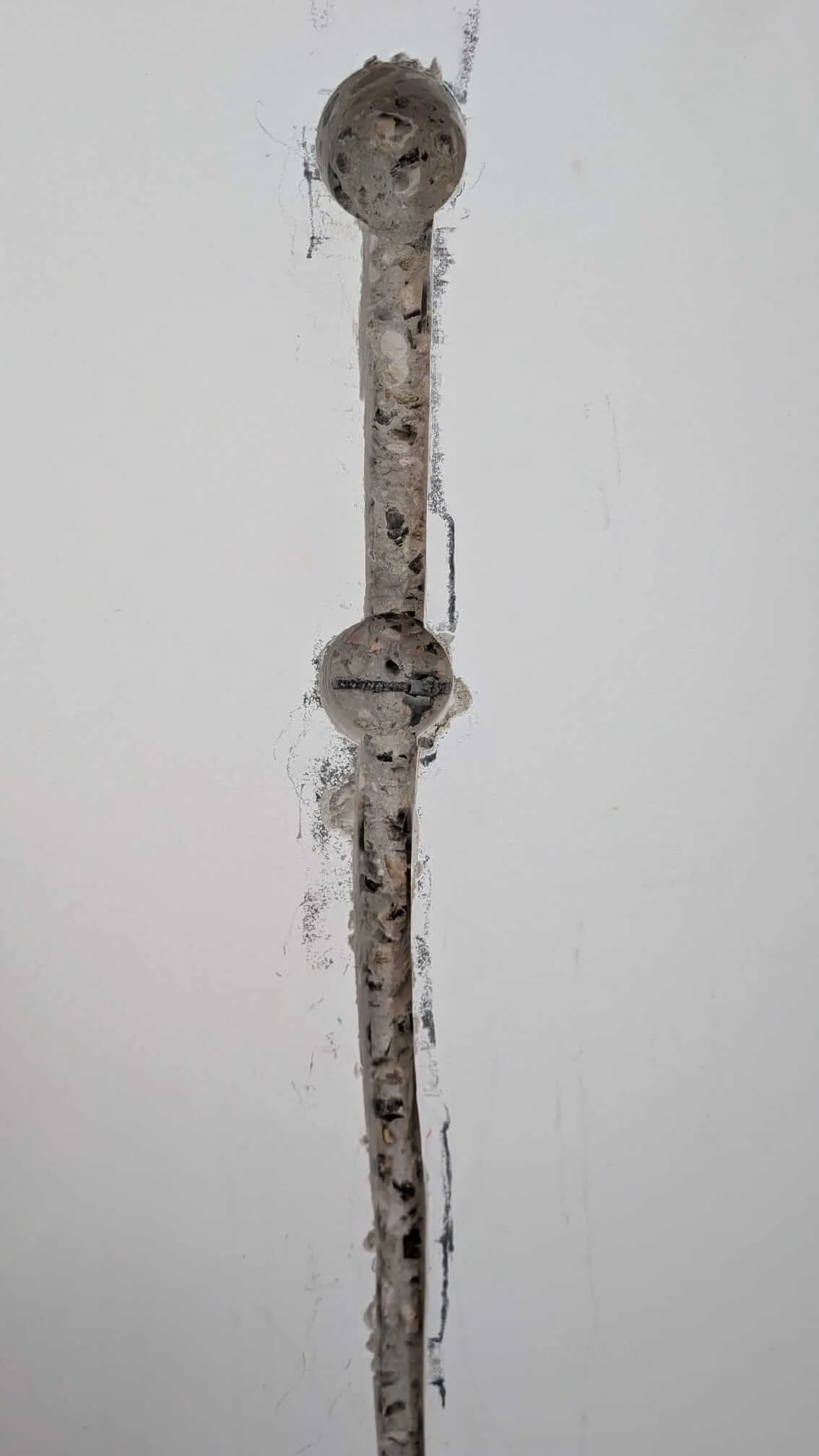 Saignée verticale réalisée à la rainureuse dans un mur en béton armé, reliant deux trous de scie cloche