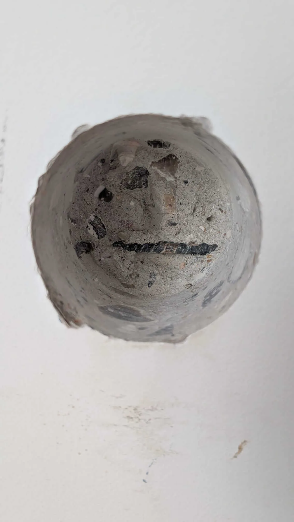 Trou percé à la scie cloche de 68 mm dans un mur en béton armé, avec un fer à béton visible au fond