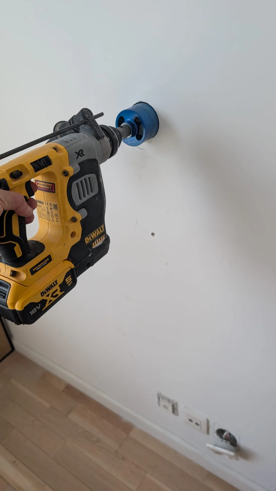 Perçage d'un mur en béton armé avec une scie cloche de 68 mm montée sur un perforateur DeWalt