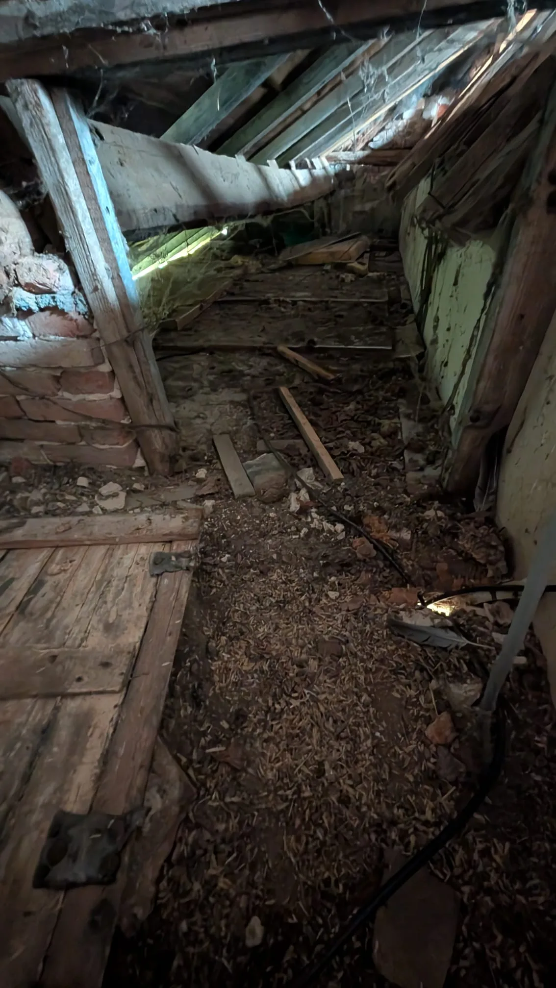 Combles encombrés de la maison normande, charpente apparente et câble électrique au sol