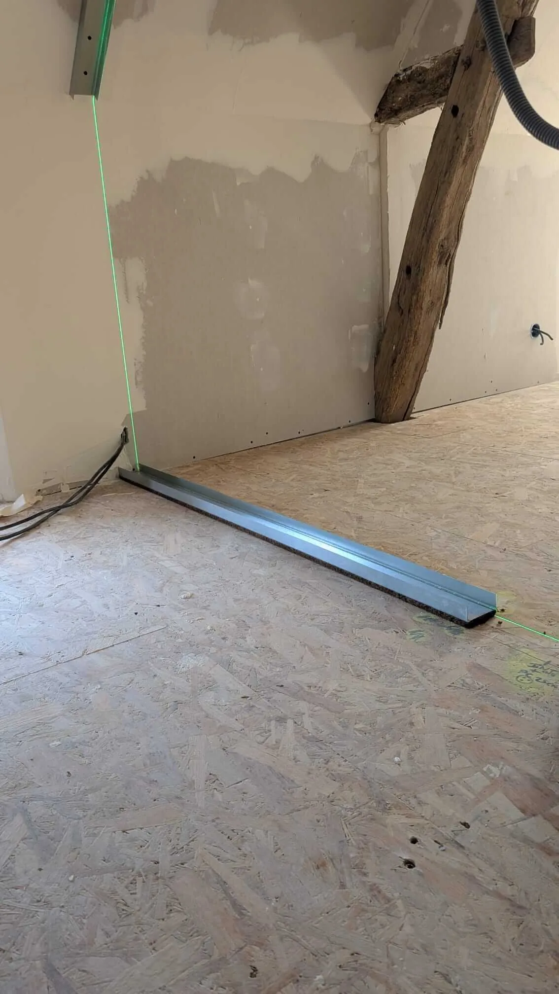 La bande de désolidarisation en fibre de bois glissée sous le rail, sur le plancher OSB